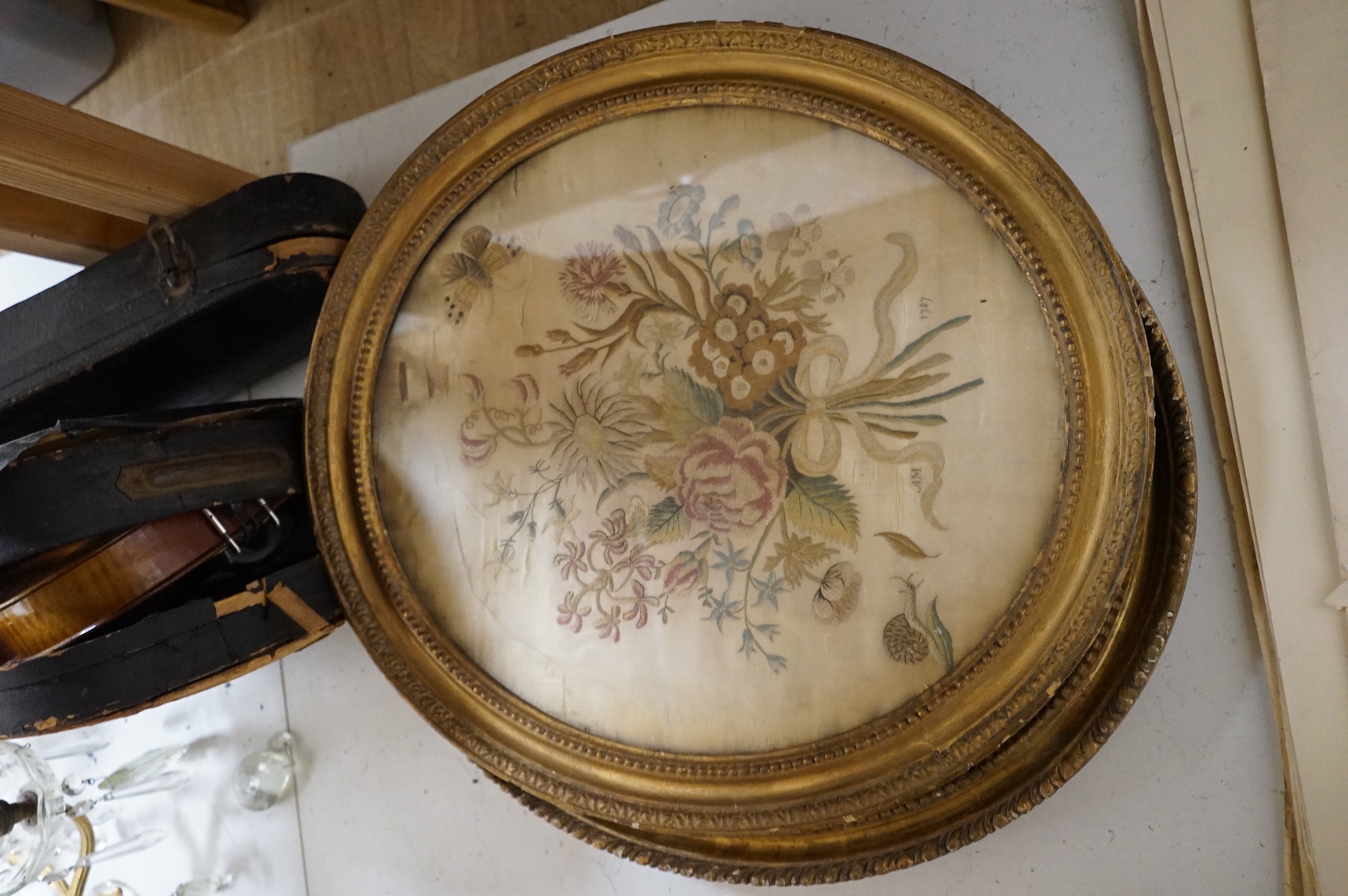 Two 18th century oval silkwork panels, one depicting flowers, monogrammed AM and dated 1787, together with a 19th century watercolour portrait of a lady, largest 42cm high